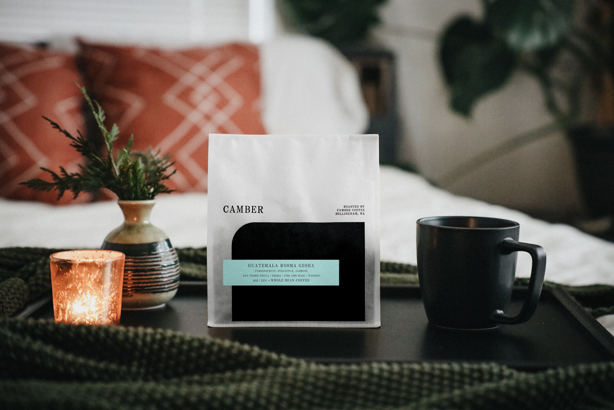Room with Bag of Camber Coffee surrounded by vase, mug and candble